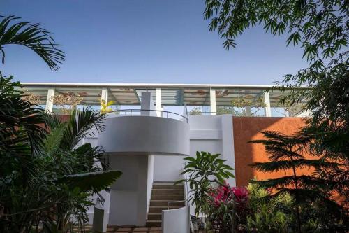 a white house with a spiral staircase in a garden at El Arbol by Da Alohas Luxury 2BHK suite Candolim in Nerul