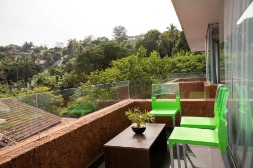 a balcony with two green chairs and a table at El Arbol by Da Alohas Luxury 2BHK suite Candolim in Nerul