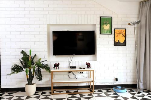 a living room with a tv on a white wall at El Arbol by Da Alohas Luxury 2BHK suite Candolim in Nerul