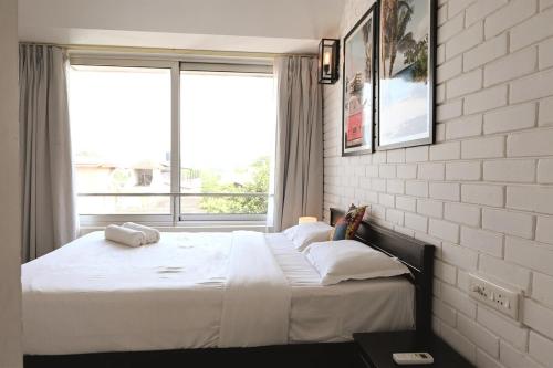 a bedroom with a large bed with a large window at El Arbol by Da Alohas Luxury 2BHK suite Candolim in Nerul