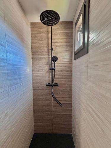 a shower in a bathroom with a wooden wall at Le Hourmigué maison avec jacuzzi à 15mn de Luchon in Cierp