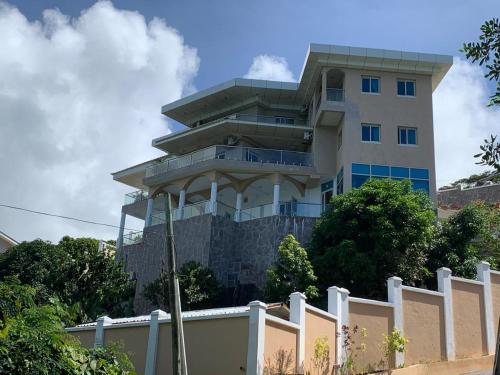 a tall building behind a white fence at Ocean Pearl Villa in Anse Royale