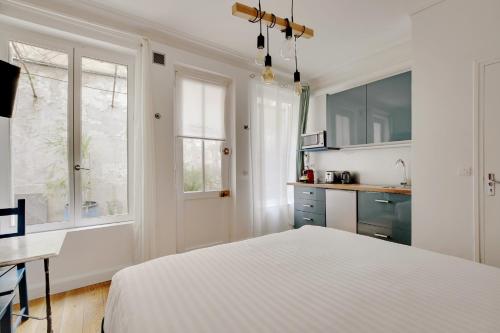 une chambre blanche avec un lit et une cuisine dans l'établissement A Sweet Studio in Montparnasse - Boulevard du Montparnasse, à Paris