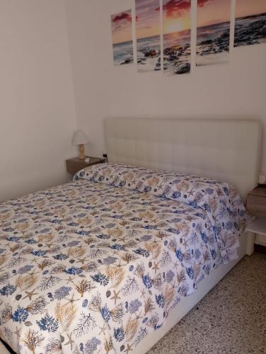 a bedroom with a bed with a floral bedspread on it at Affittacamere Casa Chiara in SantʼAntìoco