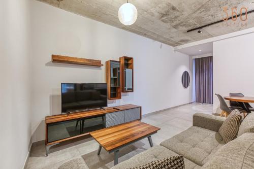 a living room with a tv and a couch and a table at The Swieqi Poolside Suites in Is-Swieqi