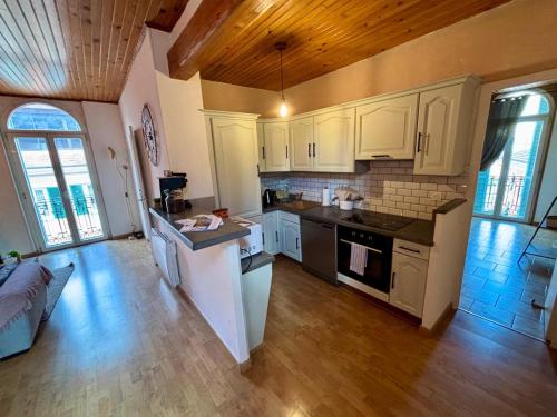 Il comprend une grande cuisine avec des placards blancs et du parquet. dans l'établissement Lumineux 3p au dernier étage, à Sospel