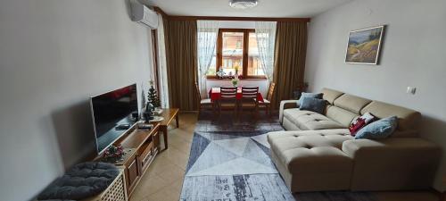 a living room with a couch and a flat screen tv at Bansko Pirin Golf & Country Club Blue Mountains View in Razlog