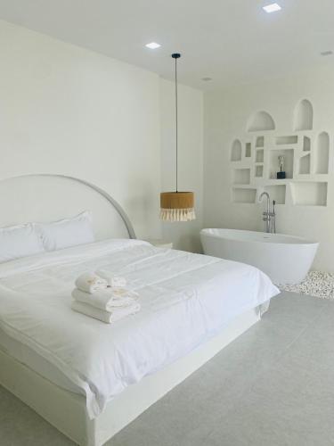 a white bedroom with a white bed and a bath tub at Huang Su Villa 7 皇宿7号泳池别墅 in Pattaya Central