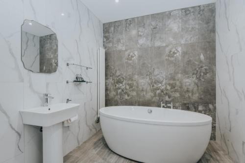 a white bathroom with a tub and a sink at Cartmel Old Grammar in Cartmel