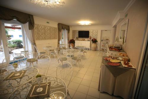 a room with tables and chairs and a kitchen at Hotel Rosa Meublé in Porto San Giorgio