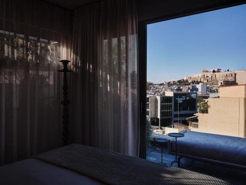 a bedroom with a window with a view of a city at Monastik Living in Athina in Athens