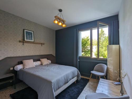 Un dormitorio con una cama y una silla y una ventana. en Les Bois de Malaguet - gite d'étape et de séjour, en Monlet