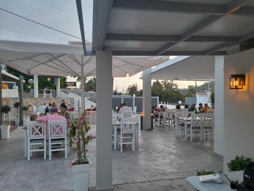 a restaurant with white tables and white chairs and people at Hotel Marina in Kolios