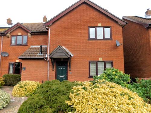 a red brick house with a green door at 18 Marriotts Way in Sheringham