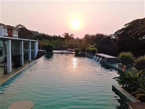 a swimming pool with the sunset in the background at Magnolia by Da Alohas El Arbol at Candolim in Nerul