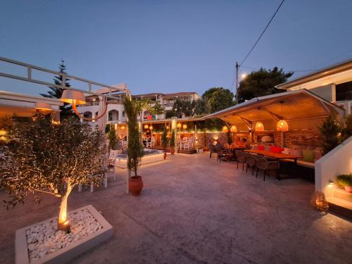 an outdoor patio with tables and chairs and trees at Hotel Marina in Kolios