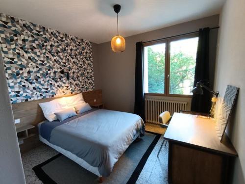 Un dormitorio con una cama y un escritorio y una ventana. en Les Bois de Malaguet - gite d'étape et de séjour, en Monlet