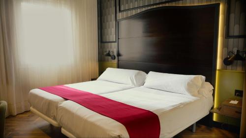 Una cama con una manta roja y blanca. en Vértice Sevilla Aljarafe, en Bormujos