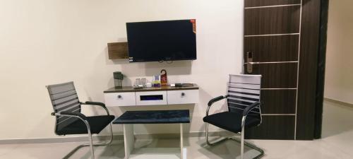 a room with a desk and two chairs and a tv at Hotel Vaishnavi Grand in Miriālgūda