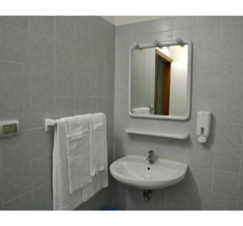 a bathroom with a sink and a mirror and towels at Gorilla African Guest House in Entebbe
