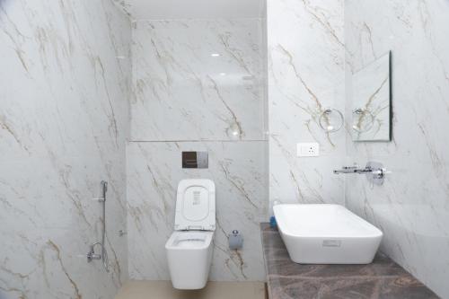 a white bathroom with a toilet and a sink at The Blessing Palace in Muzaffarpur