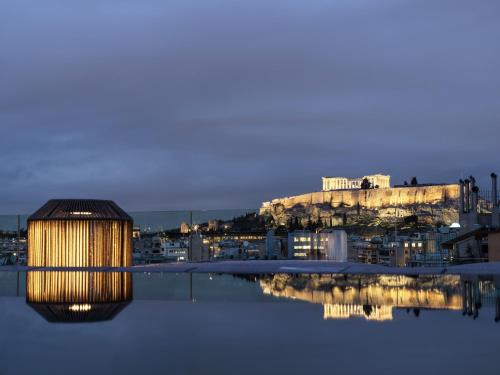 a building with a reflection in the water at night at Monastik Living in Athina in Athens