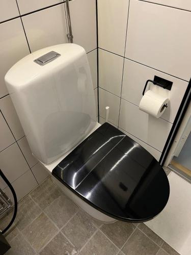 a toilet with a black seat and a toilet paper dispenser at Stylish home in Tikkakoski in Tikkakoski