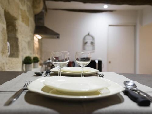 - une table avec 2 assiettes blanches et des verres à vin dans l'établissement La Petite Salamandre, à Sarlat-la-Canéda