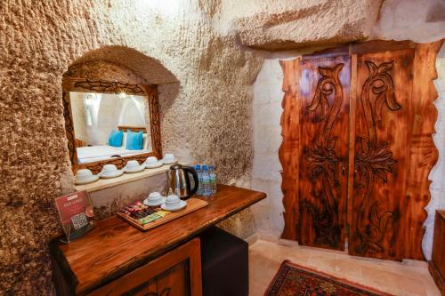 Habitación con espejo y puerta de madera. en Angel Cappadocia Cave Hotel, en Göreme
