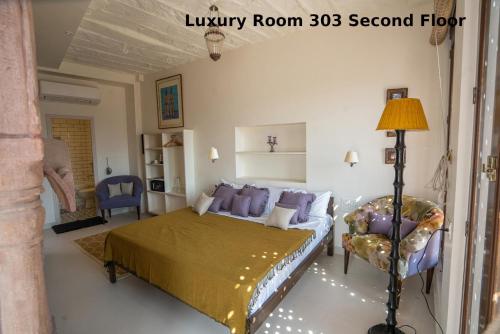 a bedroom with a king sized bed and a chair at Aakash Heritage Haveli in Jodhpur