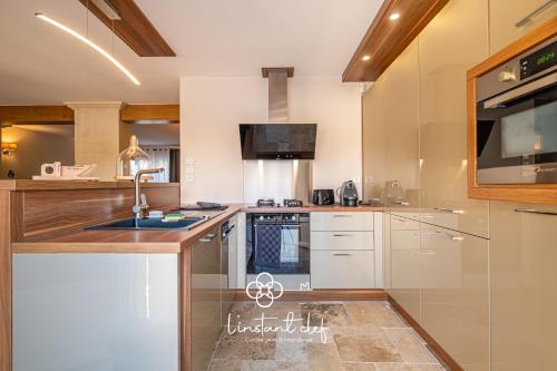 une cuisine avec un évier et une cuisinière four supérieur dans l'établissement Cocon Familial & Terrasse - Pôle Santé Sud - 10mn Circuit des 24H - L'Instant Clef, au Mans