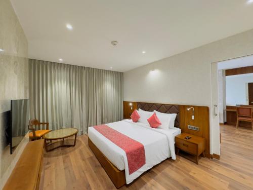 a hotel room with a bed and a television at Gokulam Grand Kozhikode in Kozhikode