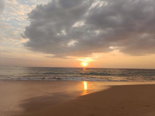 a sunset on a beach with the ocean at Green Villa Ahungalla in Balapitiya