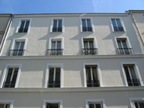 - un grand bâtiment blanc avec des fenêtres et des balcons dans l'établissement Charming apartment in Montmartre, à Paris