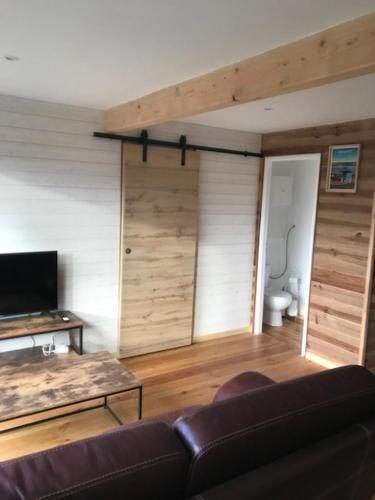 un salon avec un canapé et une télévision dans l'établissement Petite Maison T2, à Talais