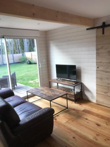 un salon avec un canapé, une table et une télévision dans l'établissement Petite Maison T2, à Talais