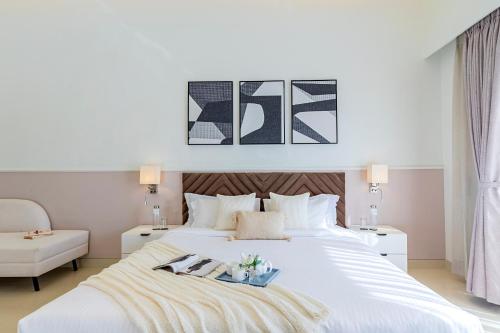 a bedroom with a large white bed and a chair at ELIVAAS Shourya Sereno - Luxe 4 BHK Villa With Pvt Pool & Garden in Lakāwās