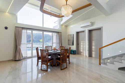 a dining room with a table and chairs at ELIVAAS Shourya Sereno - Luxe 4 BHK Villa With Pvt Pool & Garden in Lakāwās