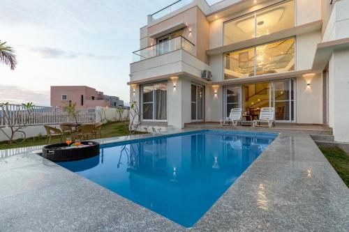 a house with a swimming pool in front of it at ELIVAAS Shourya Sereno - Luxe 4 BHK Villa With Pvt Pool & Garden in Lakāwās