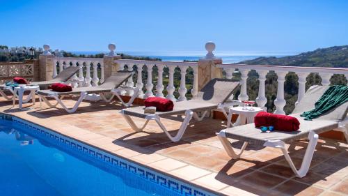 un gruppo di sedie sedute accanto a una piscina di Casa Amparo Casitas Select a Frigiliana