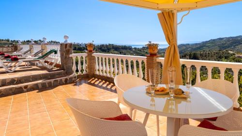 un tavolo con sedie e un ombrellone su un balcone di Casa Amparo Casitas Select a Frigiliana