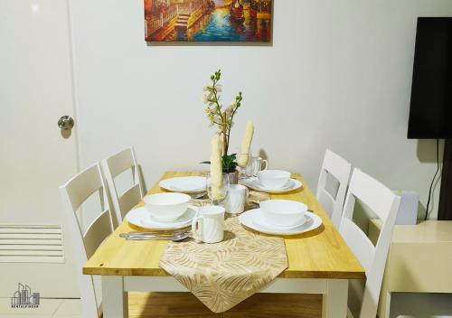 a dining room table with white chairs and a wooden table with plates at Palawan Luxury 2BR Condo with Pool, Gym & Parking - B1 5Kunzite in Puerto Princesa City