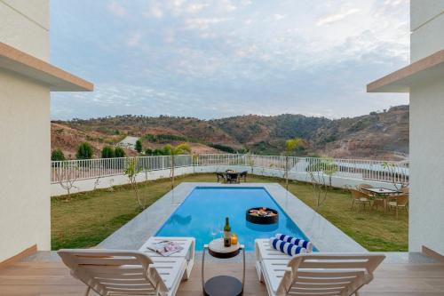 a swimming pool with chairs and a patio with a view at ELIVAAS Shourya Sereno - Luxe 4 BHK Villa With Pvt Pool & Garden in Lakāwās