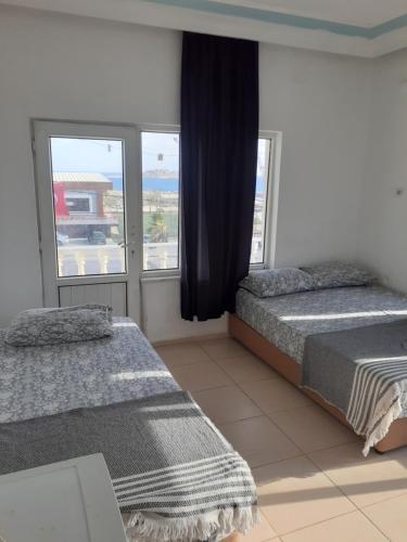 a bedroom with two beds and a large window at Huzur Pansiyon in Aydıncık