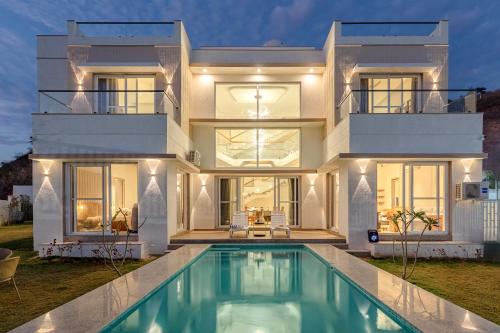 a house with a swimming pool in front of it at ELIVAAS Shourya Sereno - Luxe 4 BHK Villa With Pvt Pool & Garden in Lakāwās