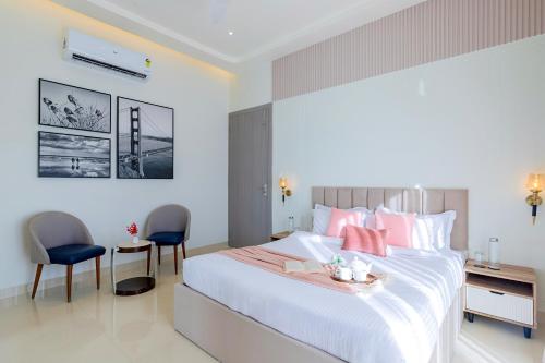 a bedroom with a large bed and two chairs at ELIVAAS Shourya Sereno - Luxe 4 BHK Villa With Pvt Pool & Garden in Lakāwās