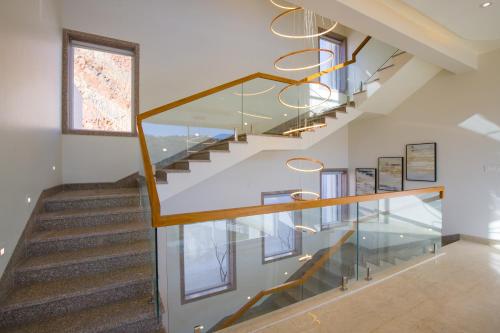 a staircase in a house with a glass railing at ELIVAAS Shourya Sereno - Luxe 4 BHK Villa With Pvt Pool & Garden in Lakāwās
