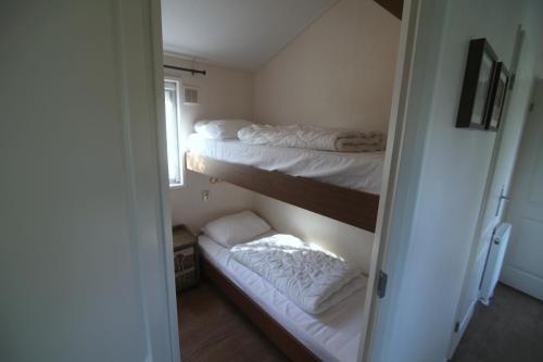 a room with three bunk beds with white sheets at Chalet park Kroondomein Giethoorn in Giethoorn