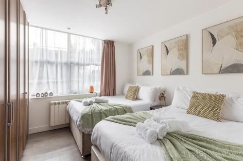 a bedroom with two beds and a window at Modern flat in central golders green in London