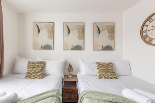 two beds in a bedroom with a clock on the wall at Modern flat in central golders green in London